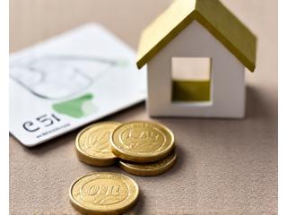 Des pièces de monnaie et une carte de crédit sur fond de maison, symbolisant le financement de projet.